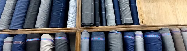 Rolls of grey and charcoal suiting with their labels