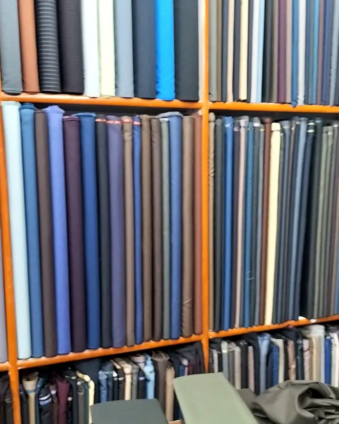 A wall of folded suiting in navy and blue shades